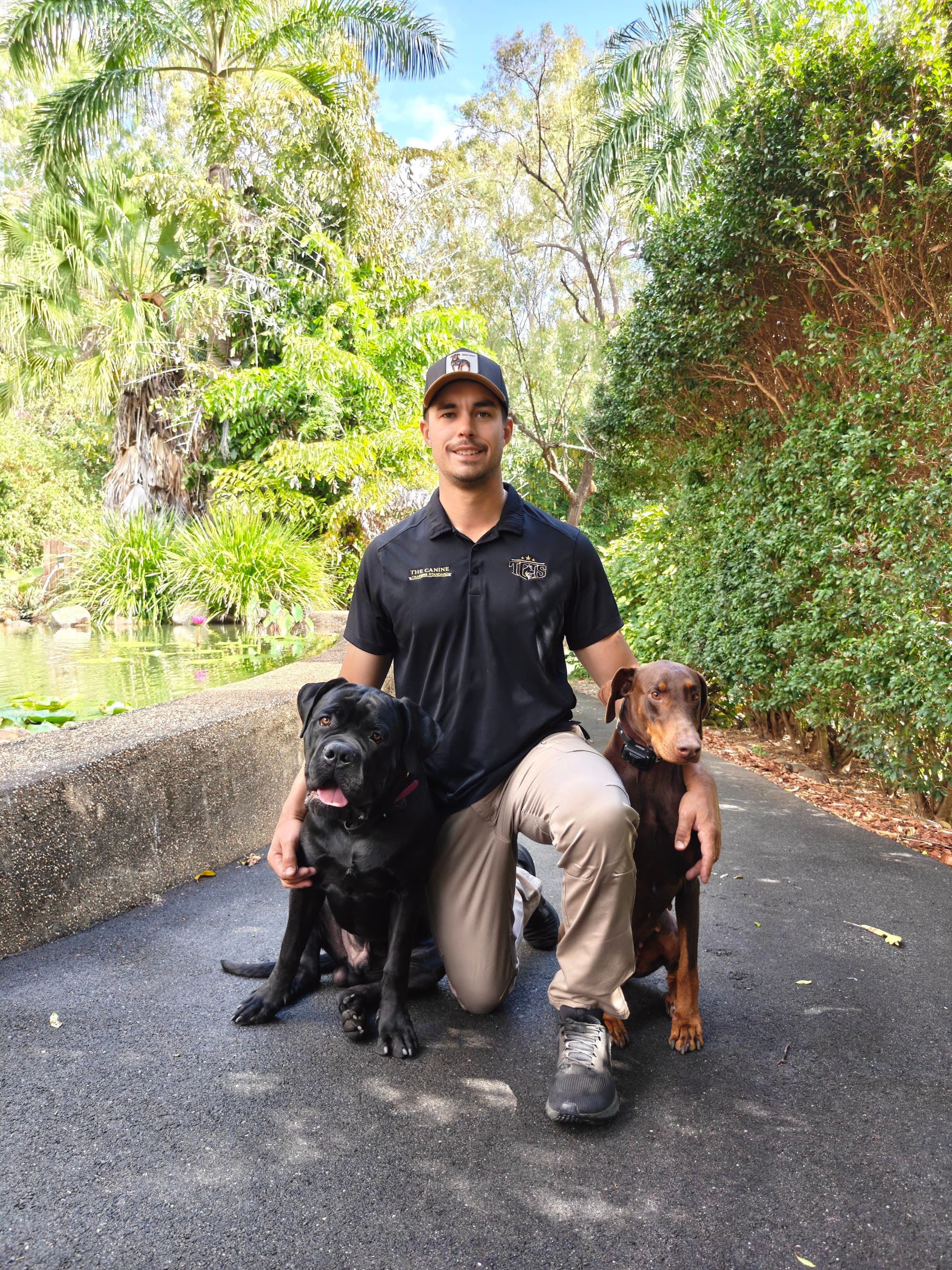 Tyler crouched between two of his trained dogs in a garden